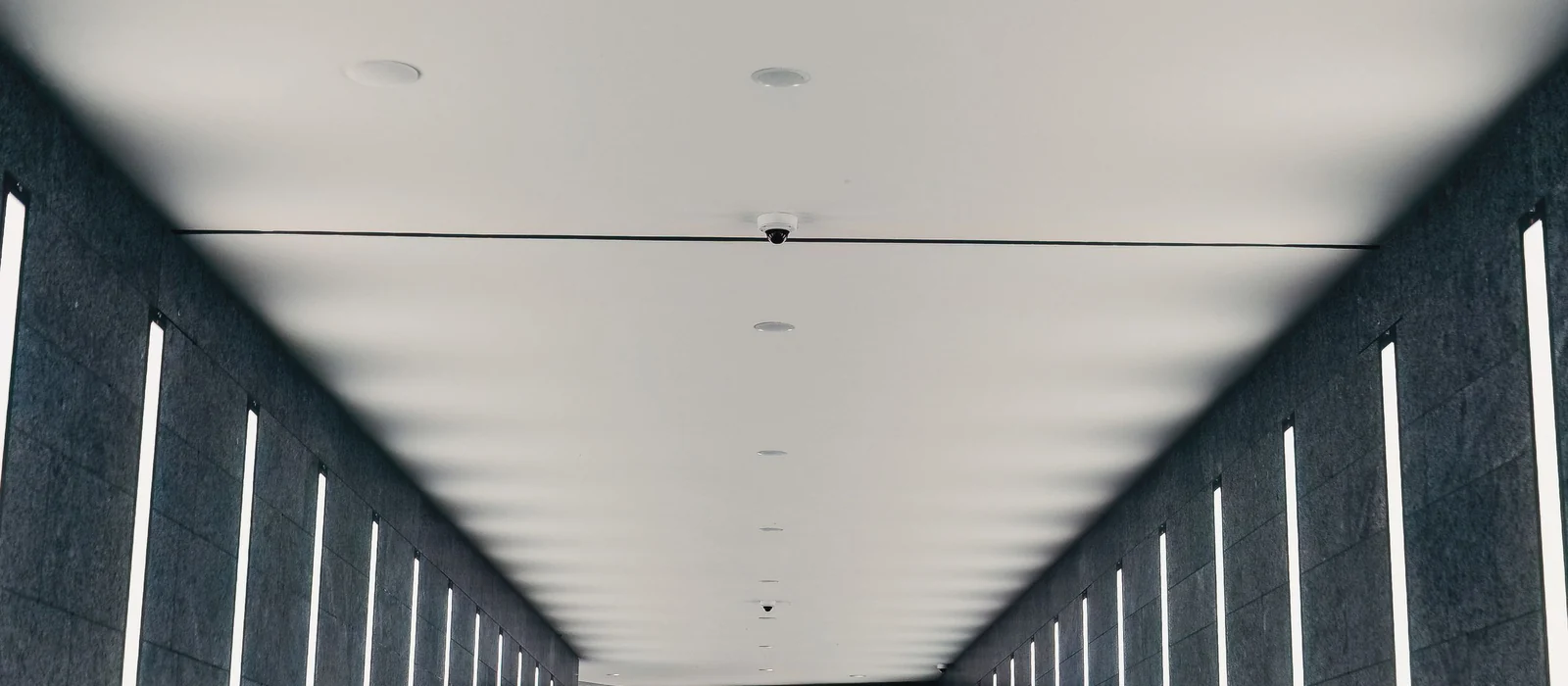 Couloir architectural blanc rythmé par un éclairage linéaire continu