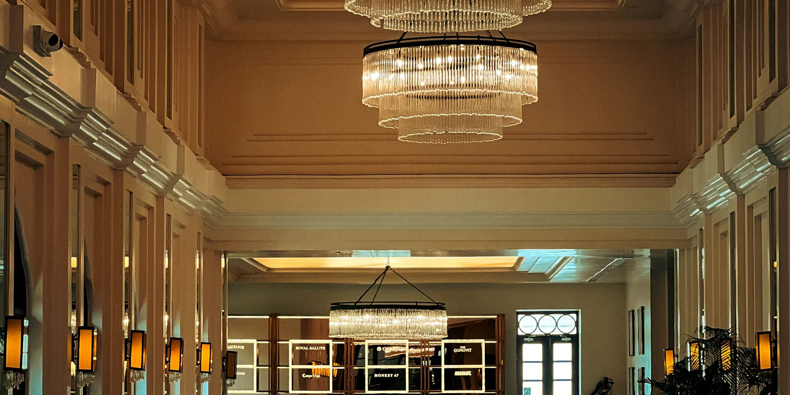 Grand hall d'hôtel éclairé par un lustre contemporain et des appliques murales