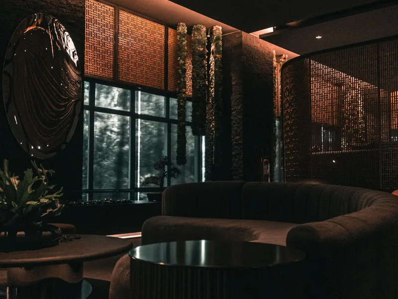 Salon d'hôtel en tonalités sombres mis en lumière par des sources chaudes