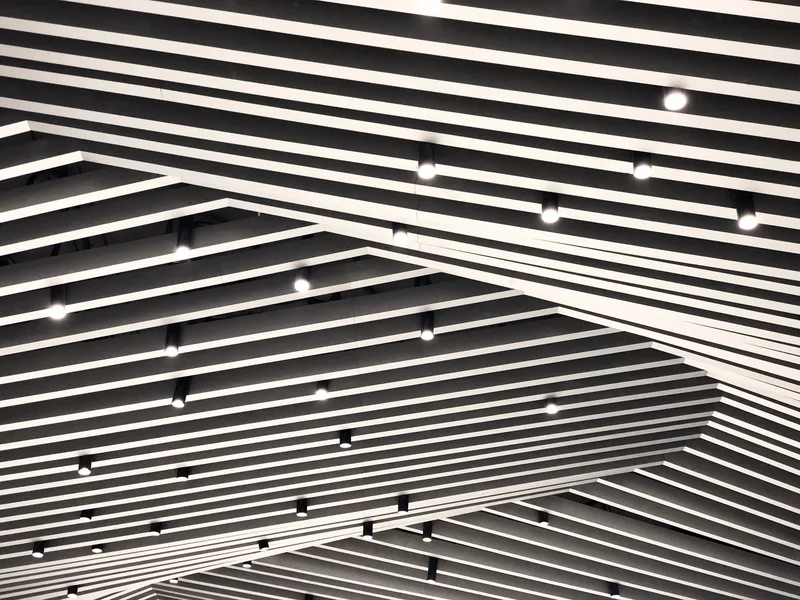 Plafond technique à lames avec éclairage encastré linéaire dans un espace tertiaire